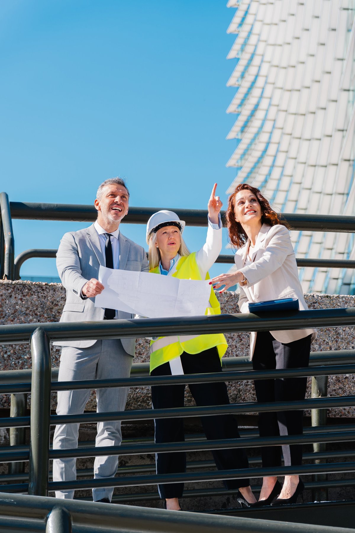Engineers examining blueprints and pointing out a detail on a building facade